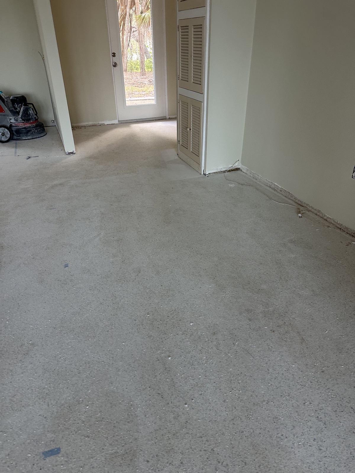 Hallway terrazzo before resurfacing, dull and gray, looking toward the glass door