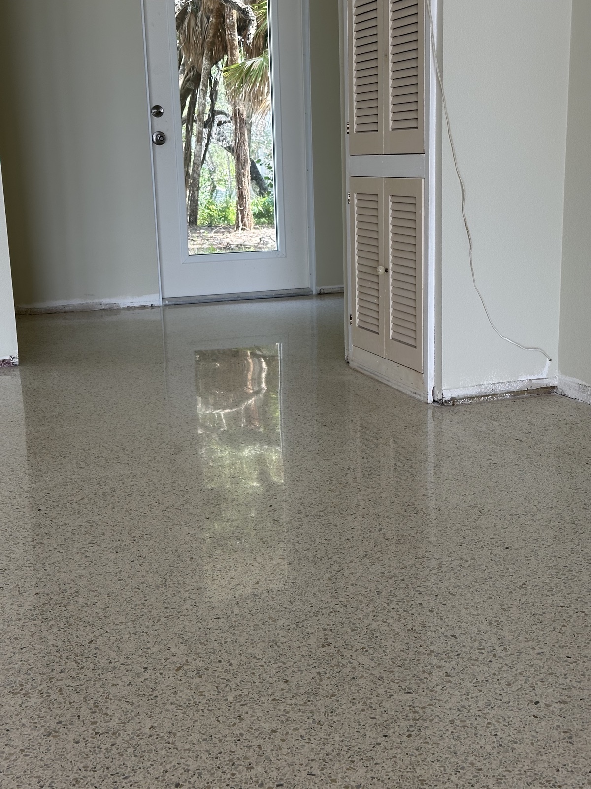 The same hallway after polishing, with the glass door reflected in the floor