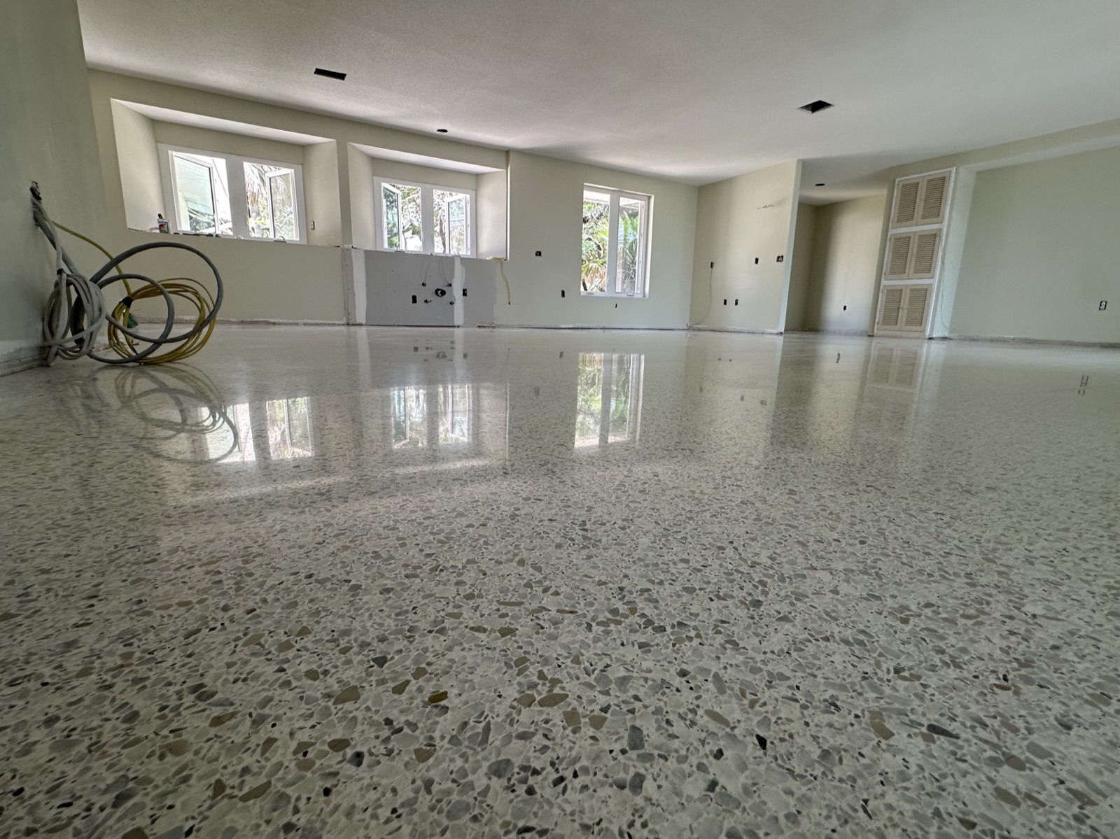 Low view across the main room after resurfacing, with the terrazzo polished and the kitchen windows reflected in it