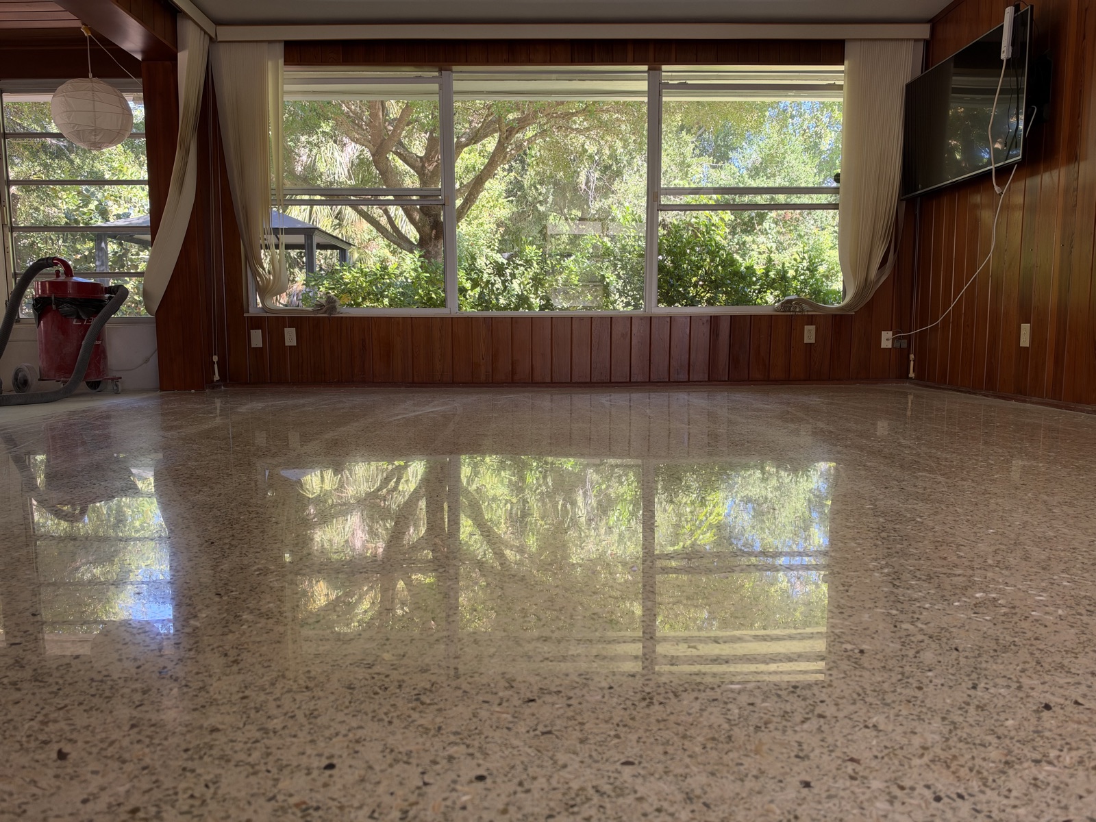 Restored terrazzo in the wood-paneled family room, reflecting the back windows.