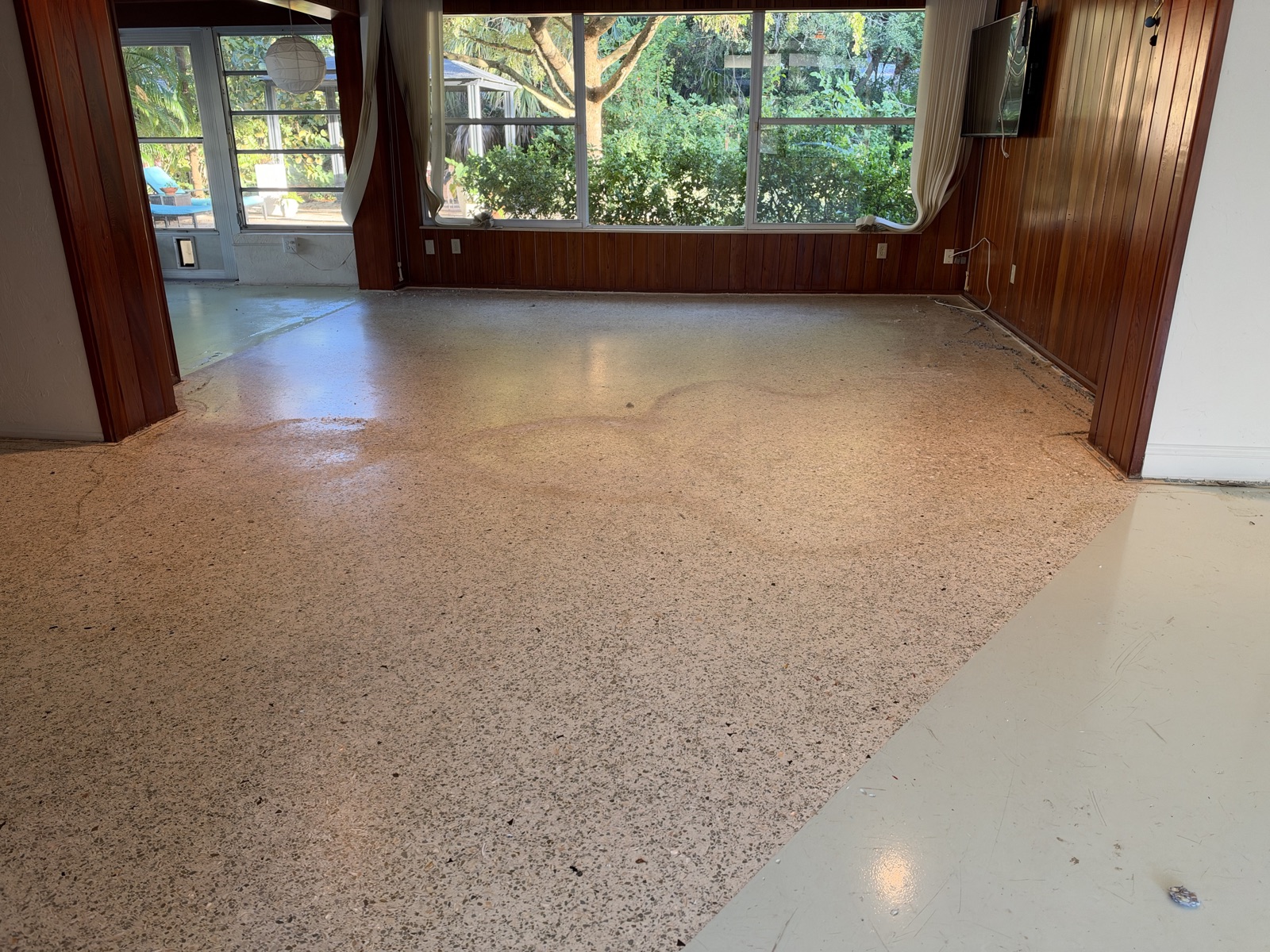 Wood-paneled family room with dull, stained terrazzo after the carpet came up.