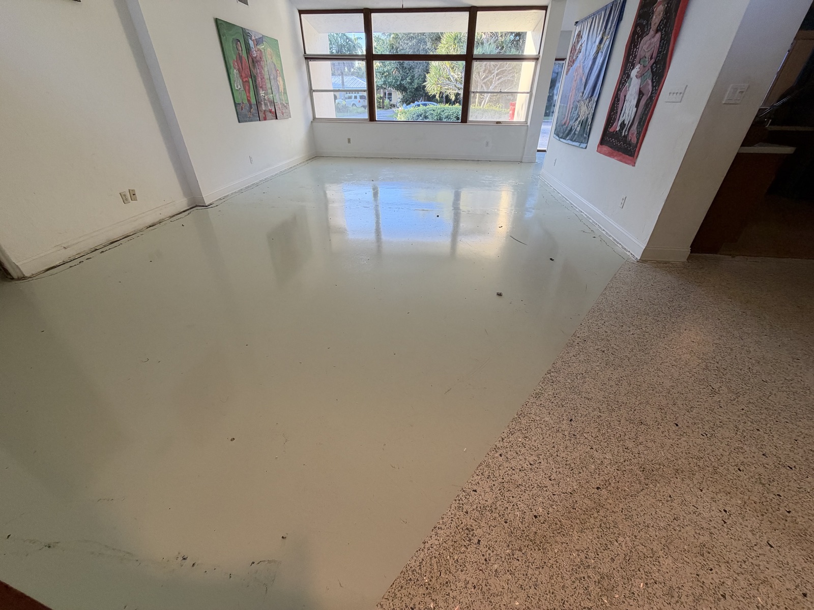 Living room with its terrazzo painted over, beside unpainted terrazzo in the next room.