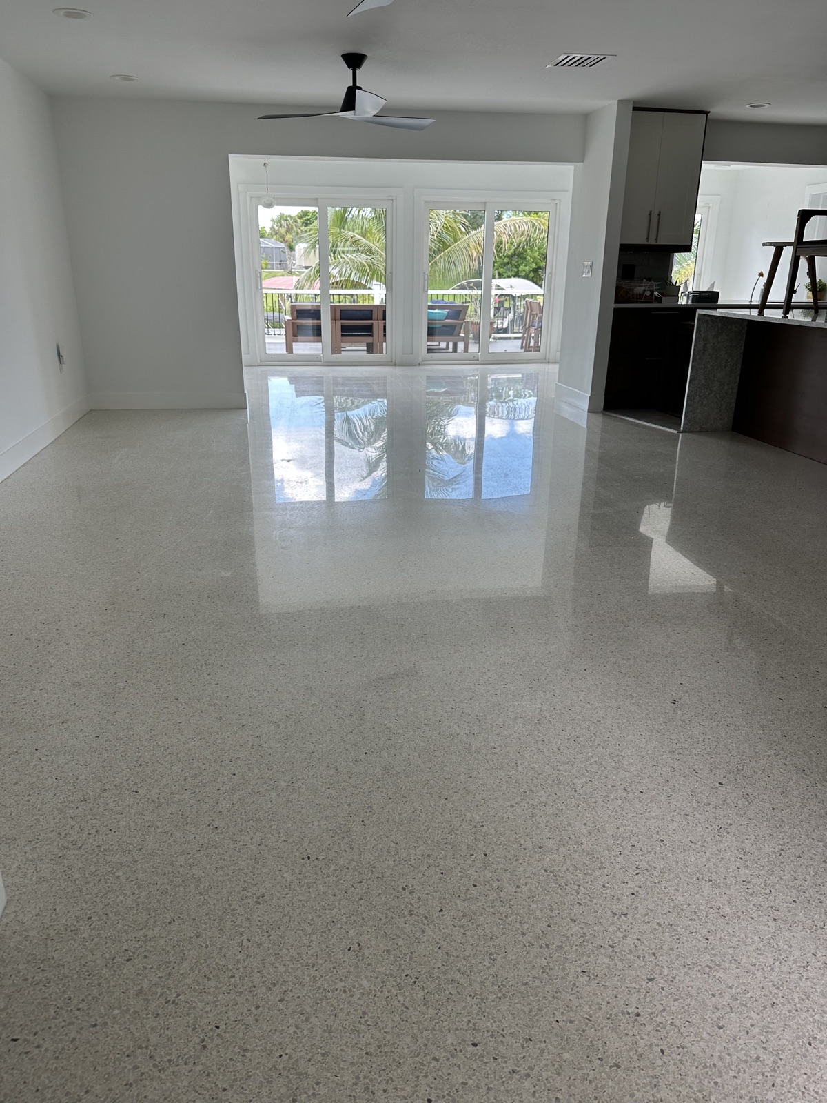 Long view across the polished living room floor to the sliding doors, with the kitchen on the right