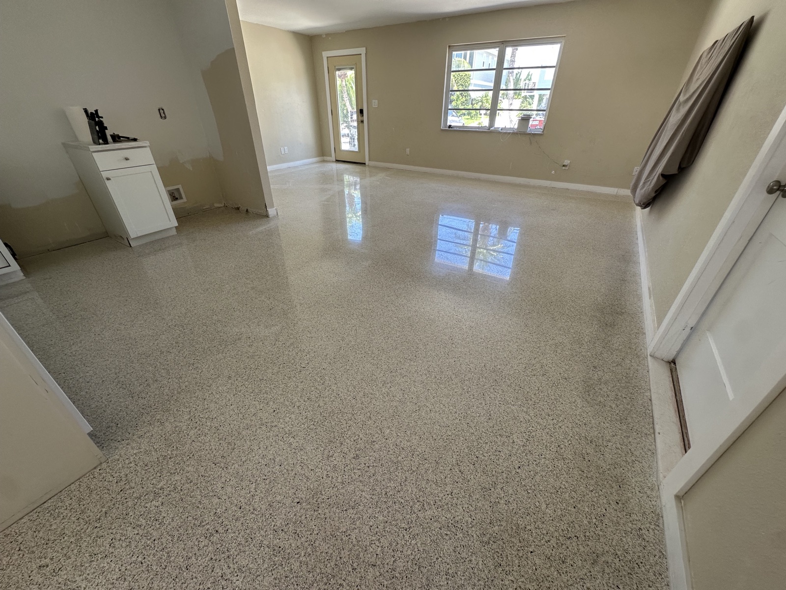The same living room after regrinding and polishing, with the front window reflected in the floor