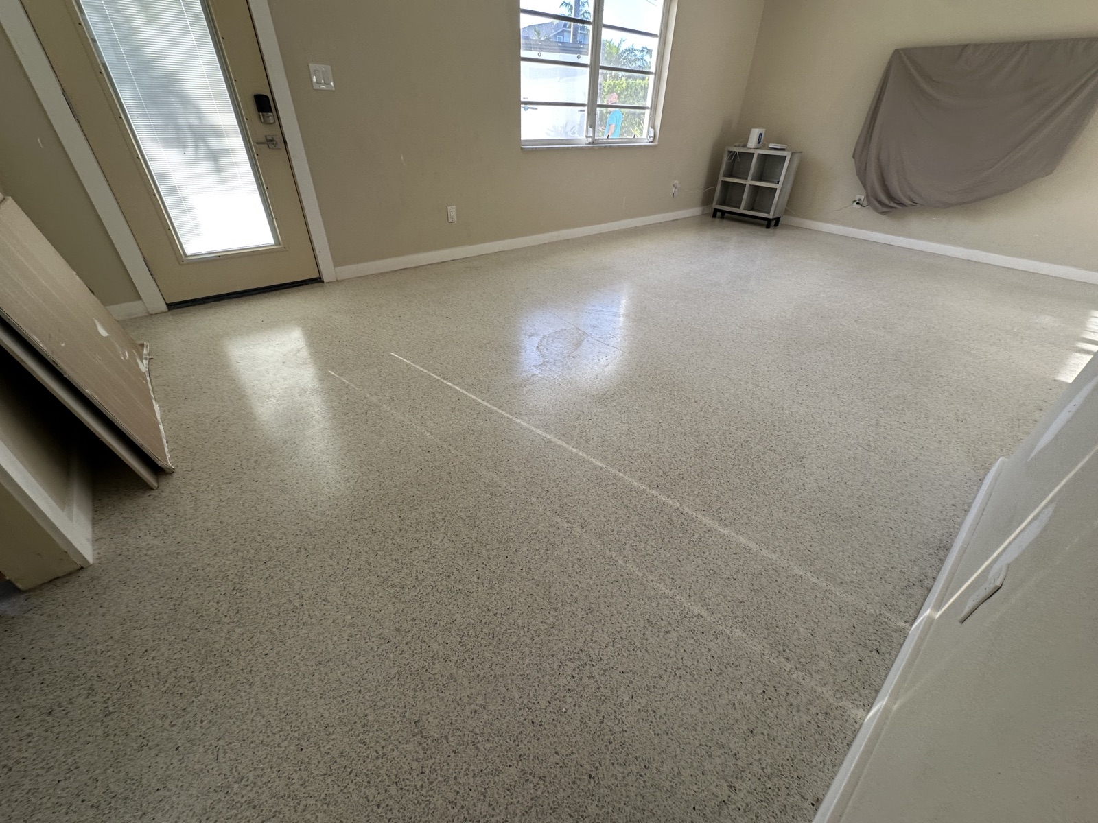 Living room terrazzo before the regrind, with a blotchy, uneven shine near the front door
