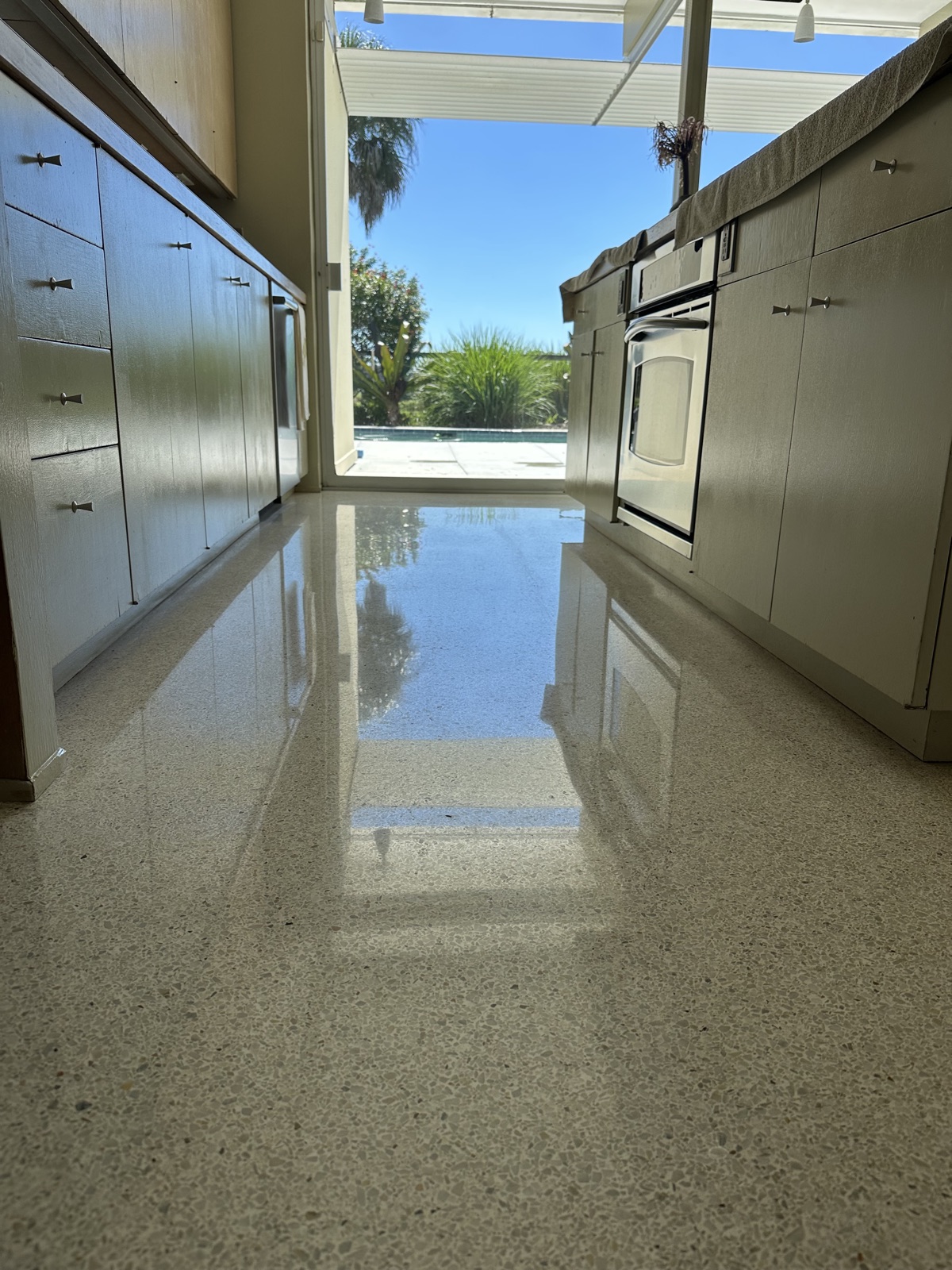 Galley kitchen terrazzo after repolishing, with an even shine between the cabinets.