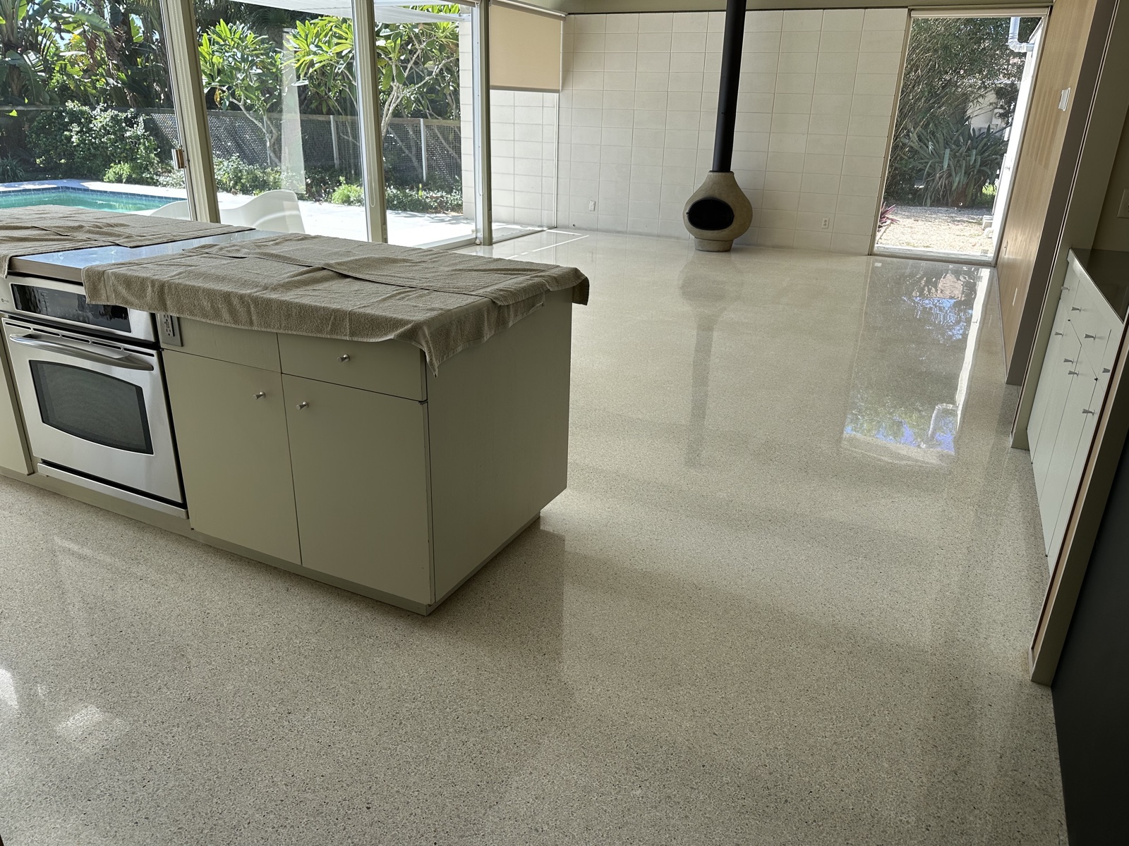 Terrazzo after repolishing, seen past the kitchen island toward the living room and fireplace.
