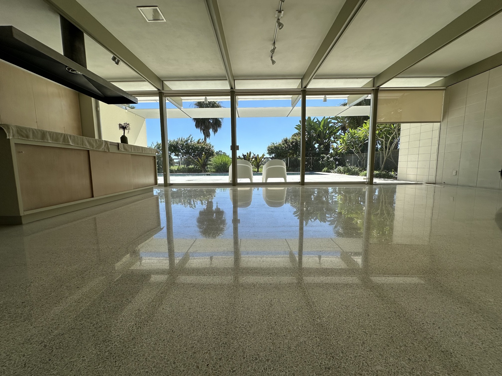 Repolished living room terrazzo under the beamed ceiling, facing the glass wall.