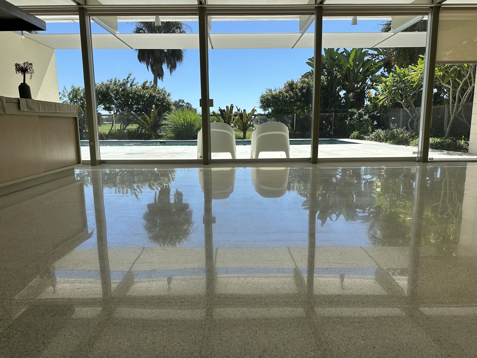Living room terrazzo after repolishing, with a high shine in front of the glass wall onto the pool.